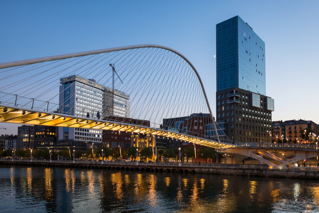 View to the Plaza de la Convivencia with the famous bridge Puente Zubizuri, The white bridge, also named Campo Volantin Bridge, is a tied arch footbridge across the Nervion River in Bilbao, Spain